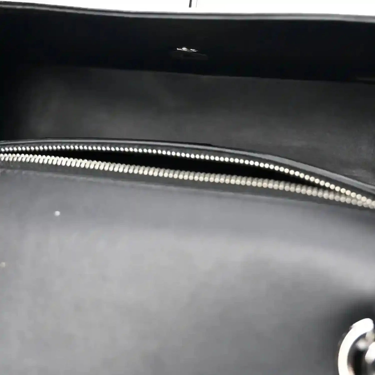 Black bag interior with silver-tone zipper edge and stitched trim.