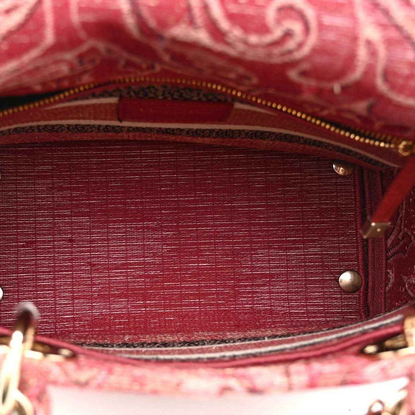 Red canvas bag interior with textured lining and gold-tone zipper trim