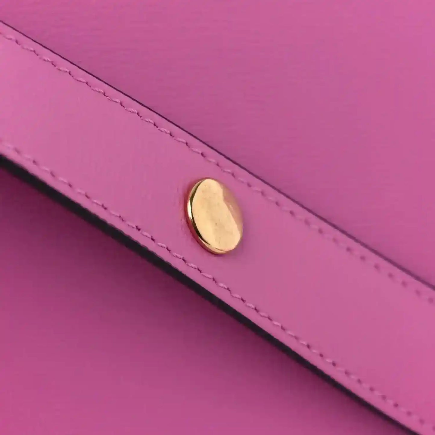 Pink leather shoulder bag flap hardware detail with gold-toned oval clasp