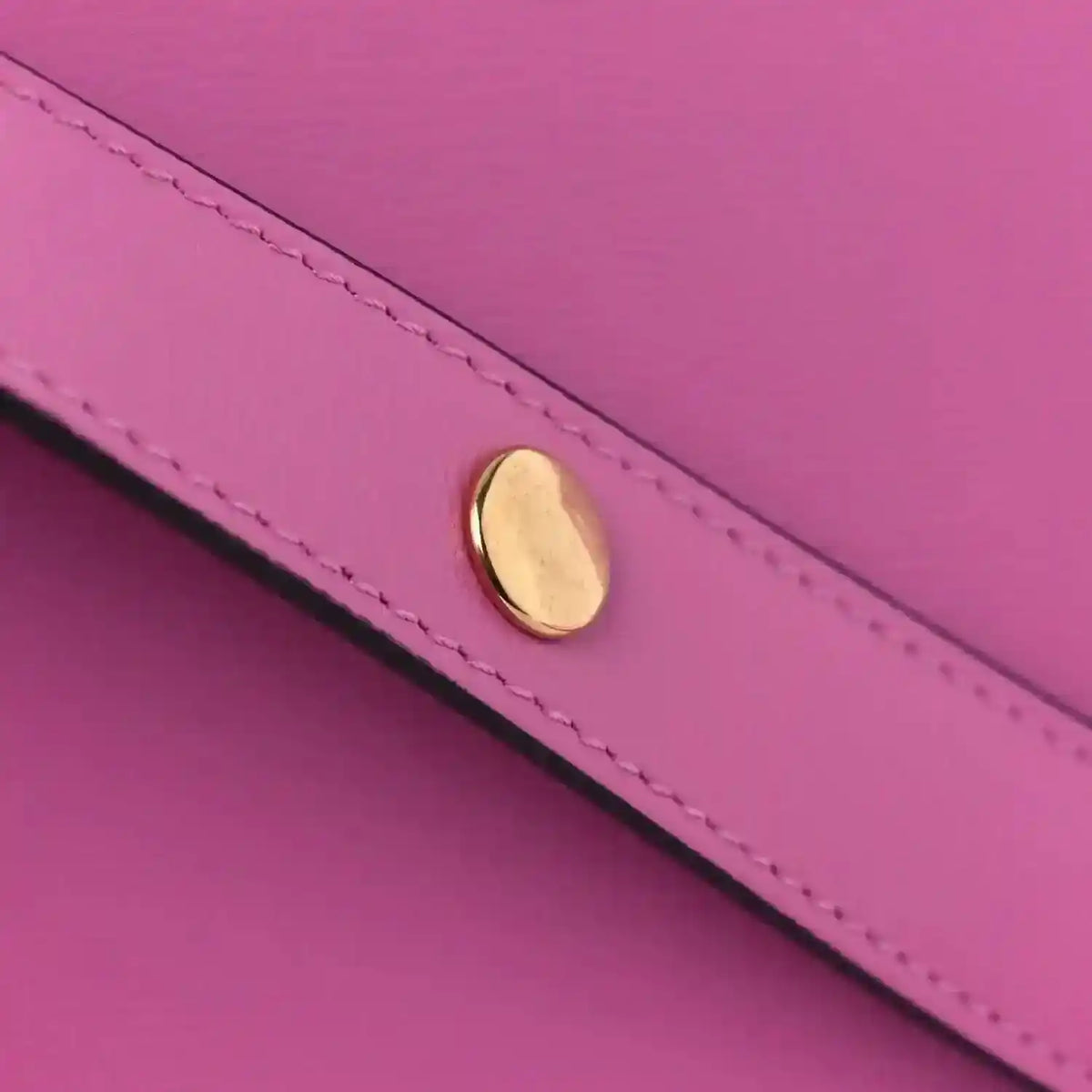 Pink leather shoulder bag flap hardware detail with gold-toned oval clasp