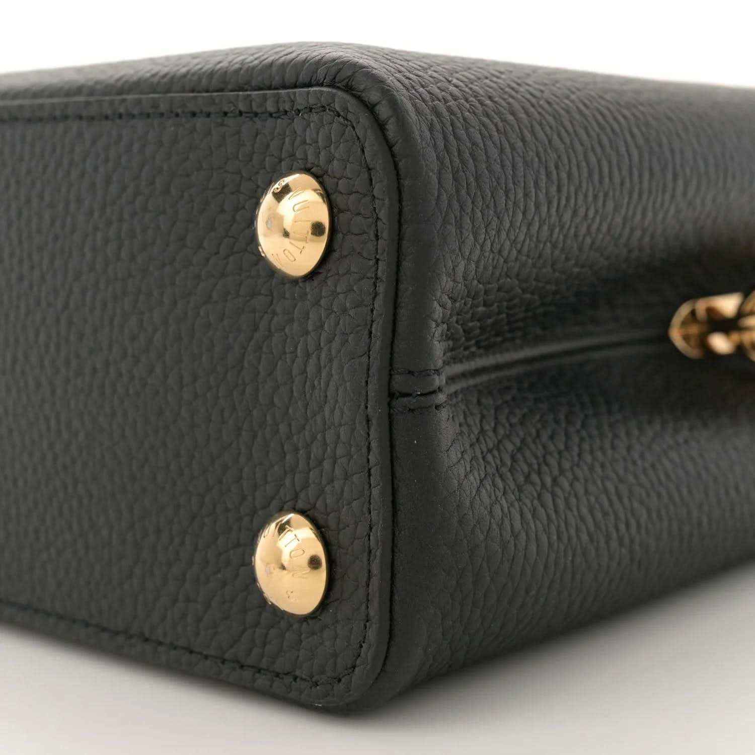 Black leather mini bag bottom corner with two gold snap buttons, close-up