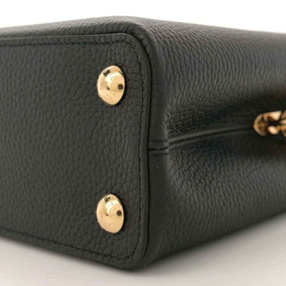 Black leather mini bag bottom corner with two gold snap buttons, close-up