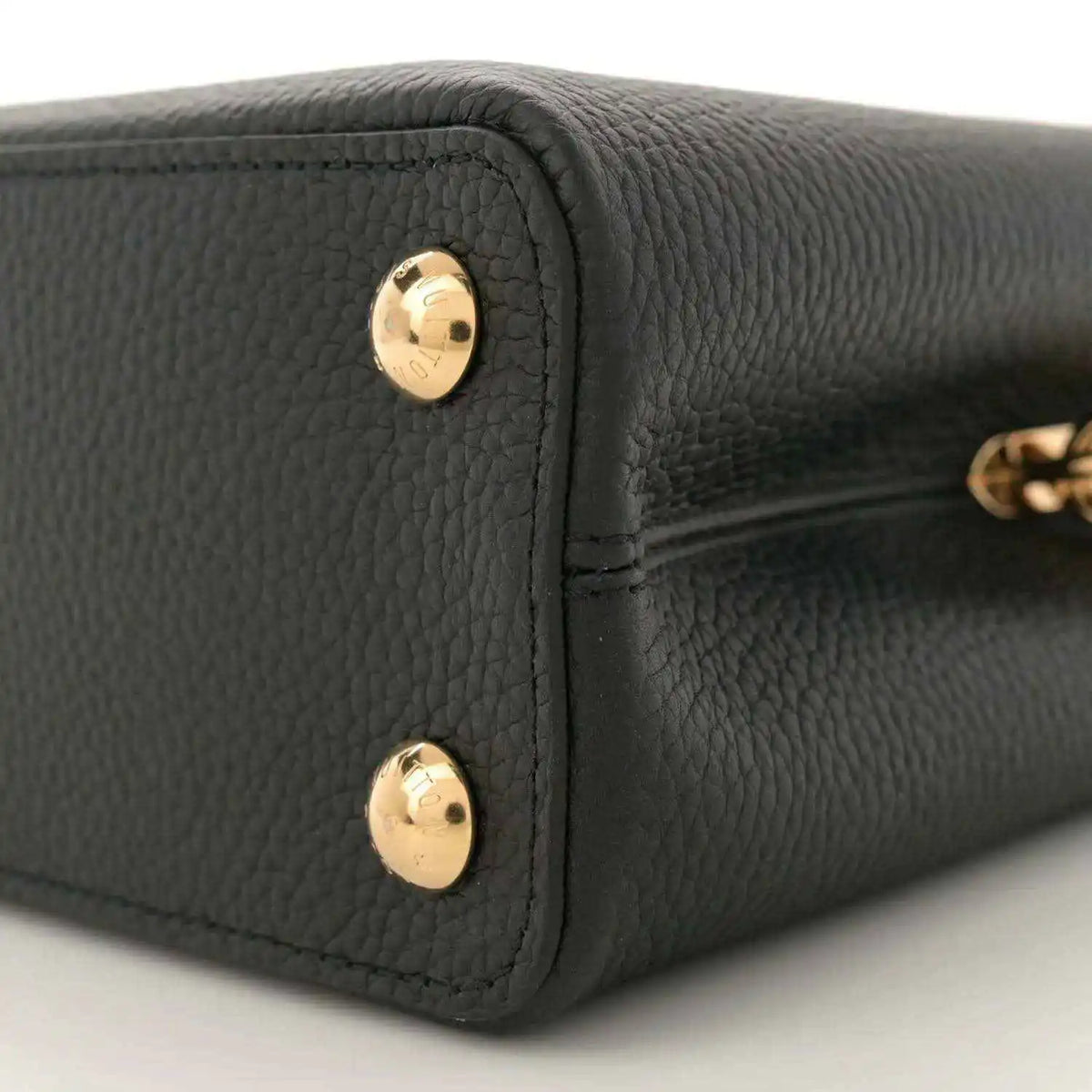 Black leather mini bag bottom corner with two gold snap buttons, close-up