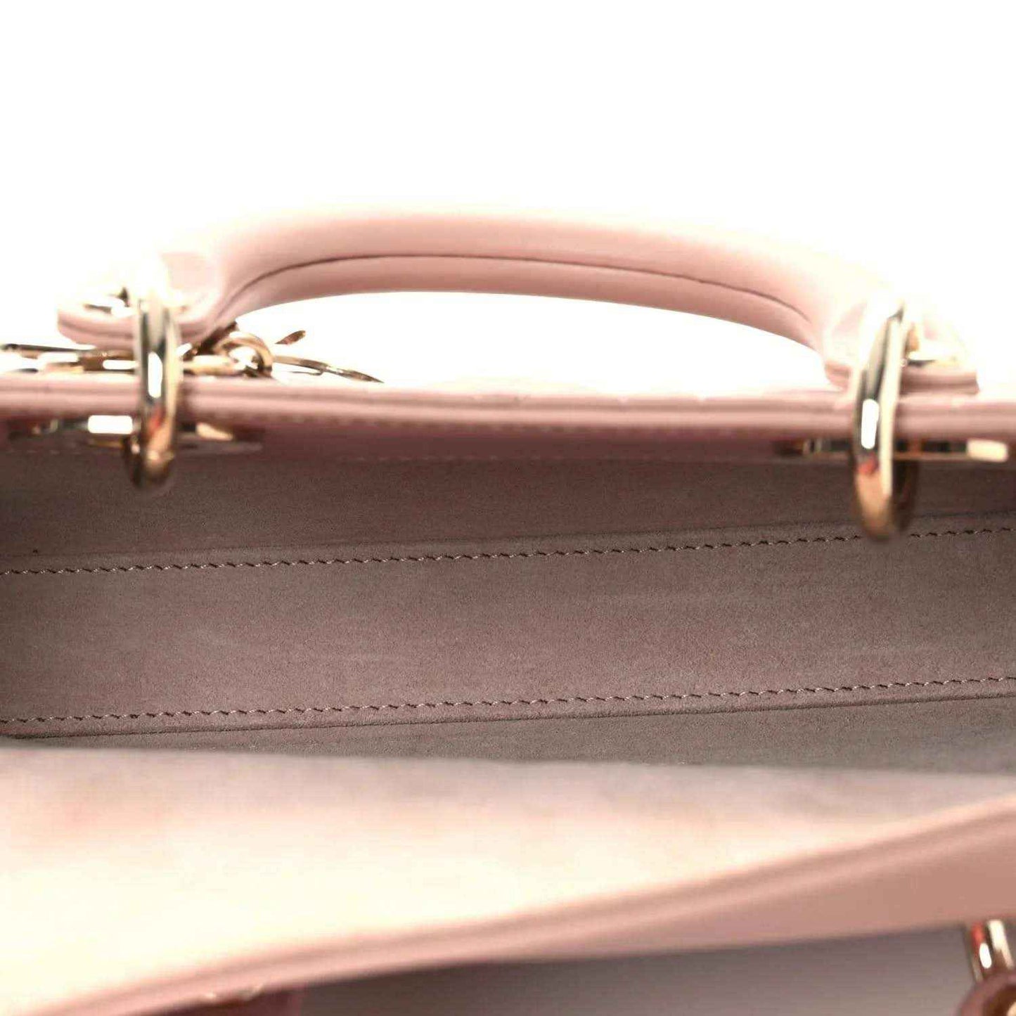 Top handle of pale pink lambskin handbag with gold-tone rings and seam stitching