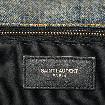 Black leather brand label reading SAINT LAURENT PARIS on denim satchel
