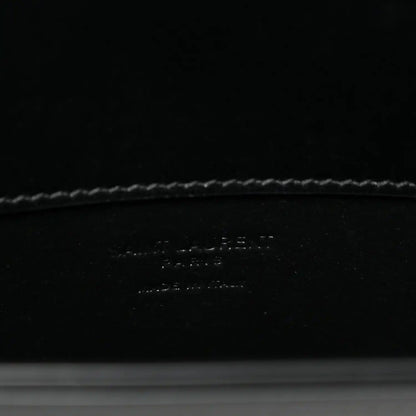 Black leather crossbody bag interior base with debossed brand text and stitching.