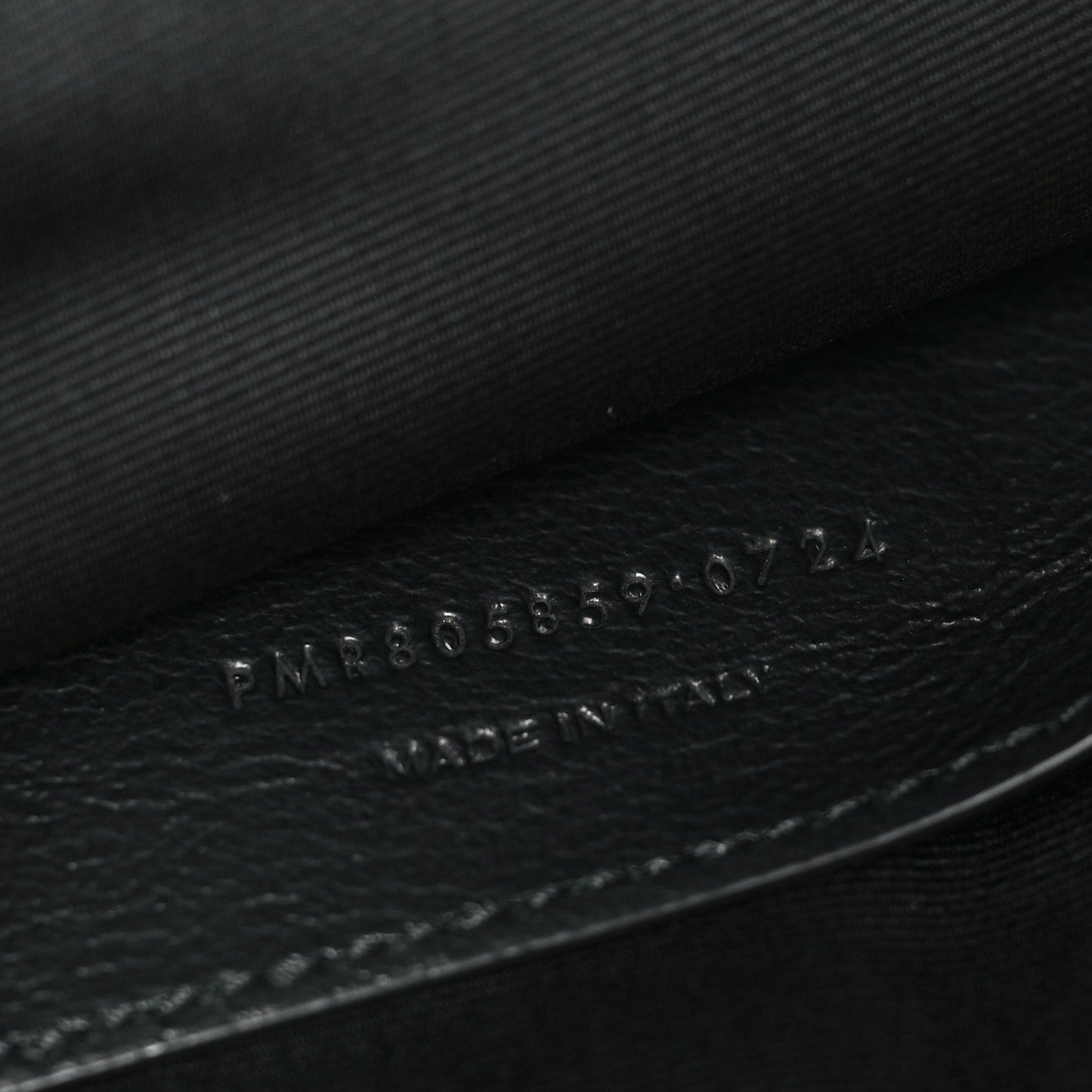 Embossed numbers on dark leather inside of Saint Laurent shoulder bag.