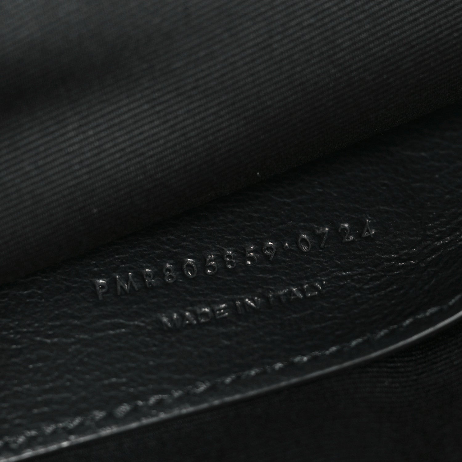 Embossed numbers on dark leather inside of Saint Laurent shoulder bag.