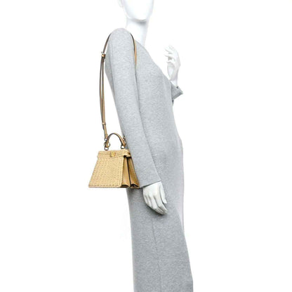 Petite raffia satchel bag worn on the arm, with tan leather strap and clasp.