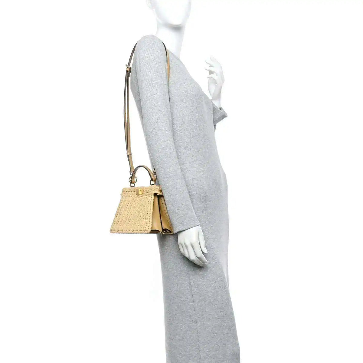 Petite raffia satchel bag worn on the arm, with tan leather strap and clasp.