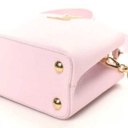 Pink leather handbag corner with two gold studs and chain strap attachment