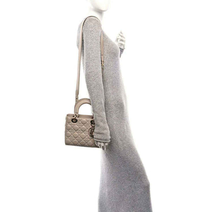 Beige quilted mini handbag with top handle and wrist strap, side view