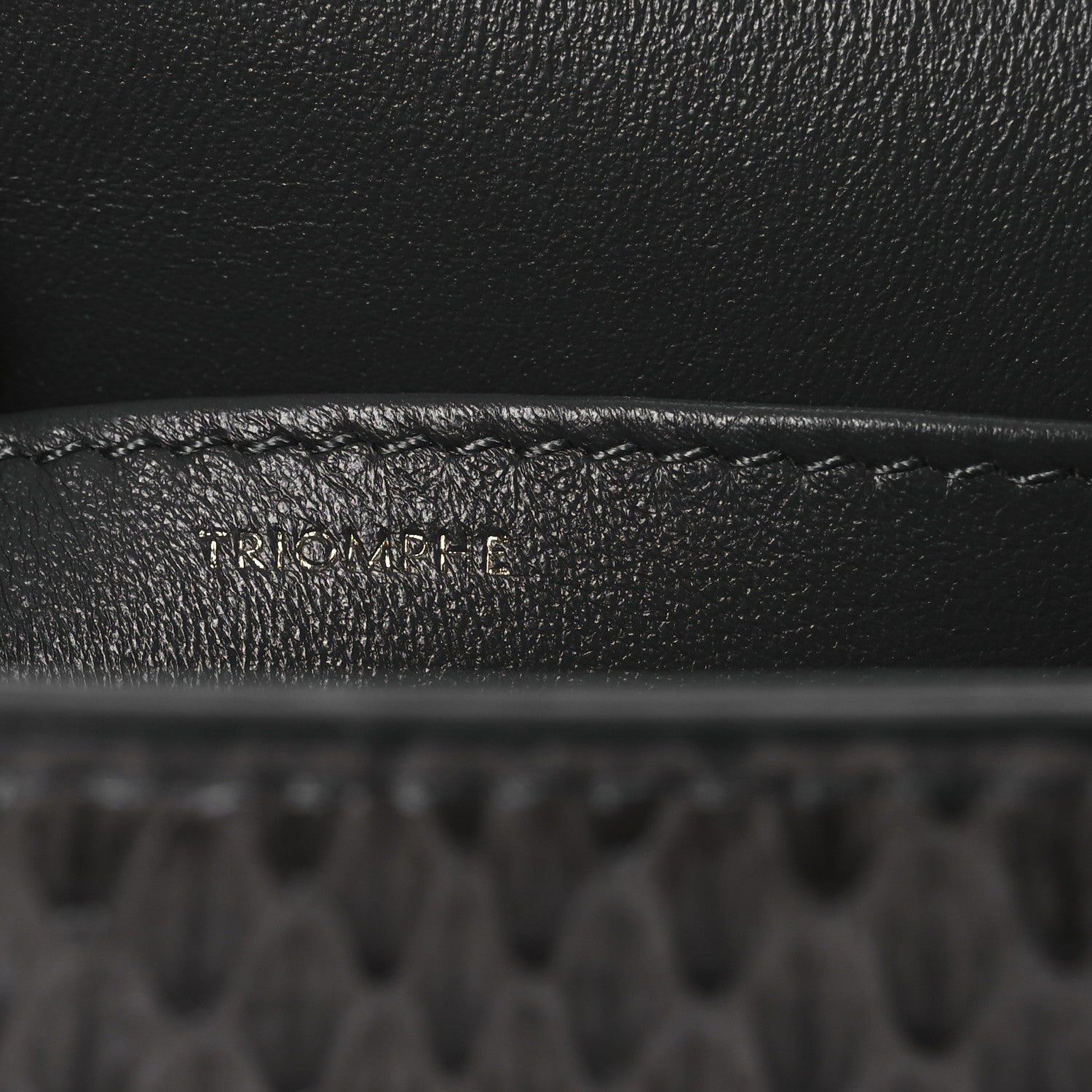 Grey snakeskin shoulder bag flap close-up with embossed brand detail