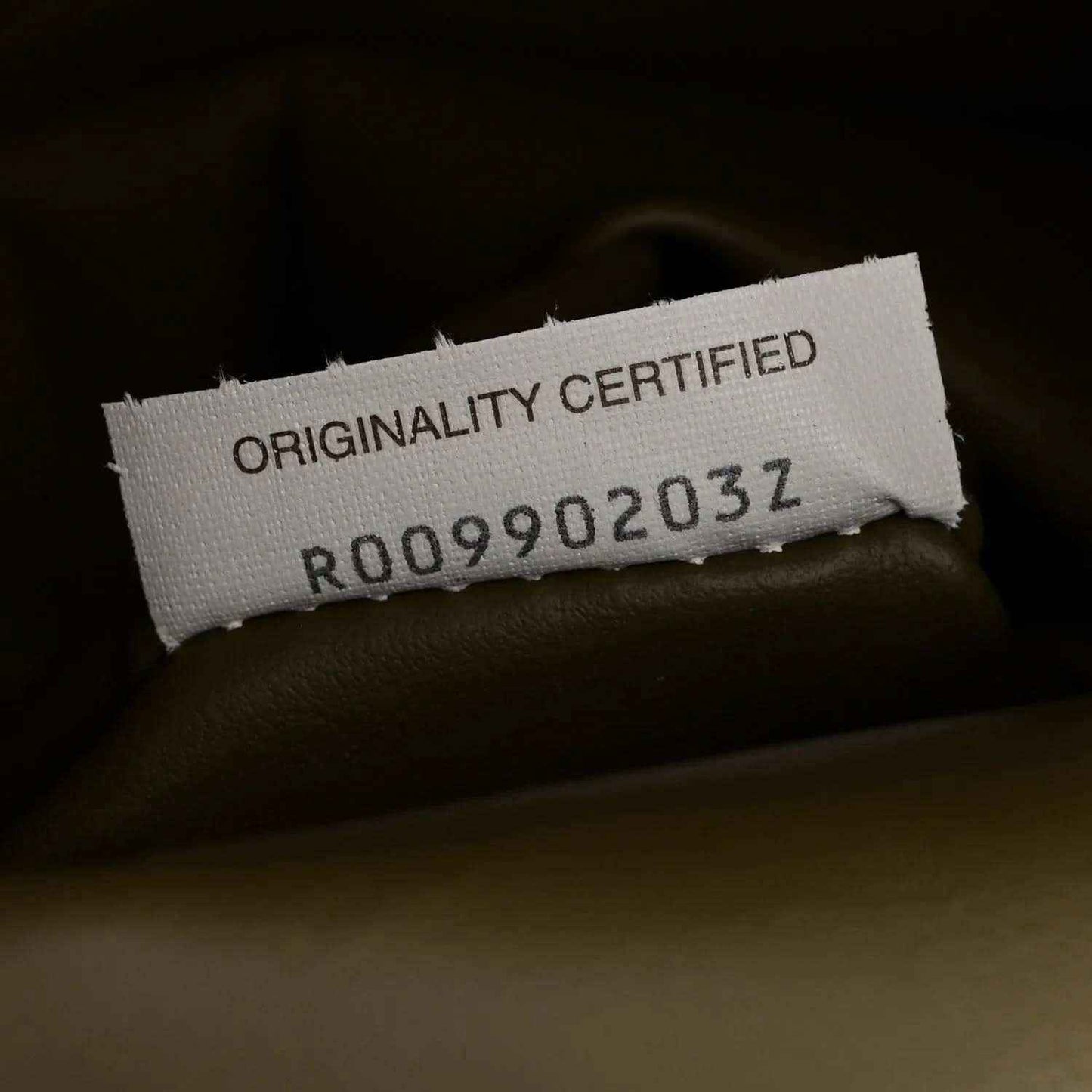 “ORIGINALITY CERTIFIED” tag inside mud green hobo bag
