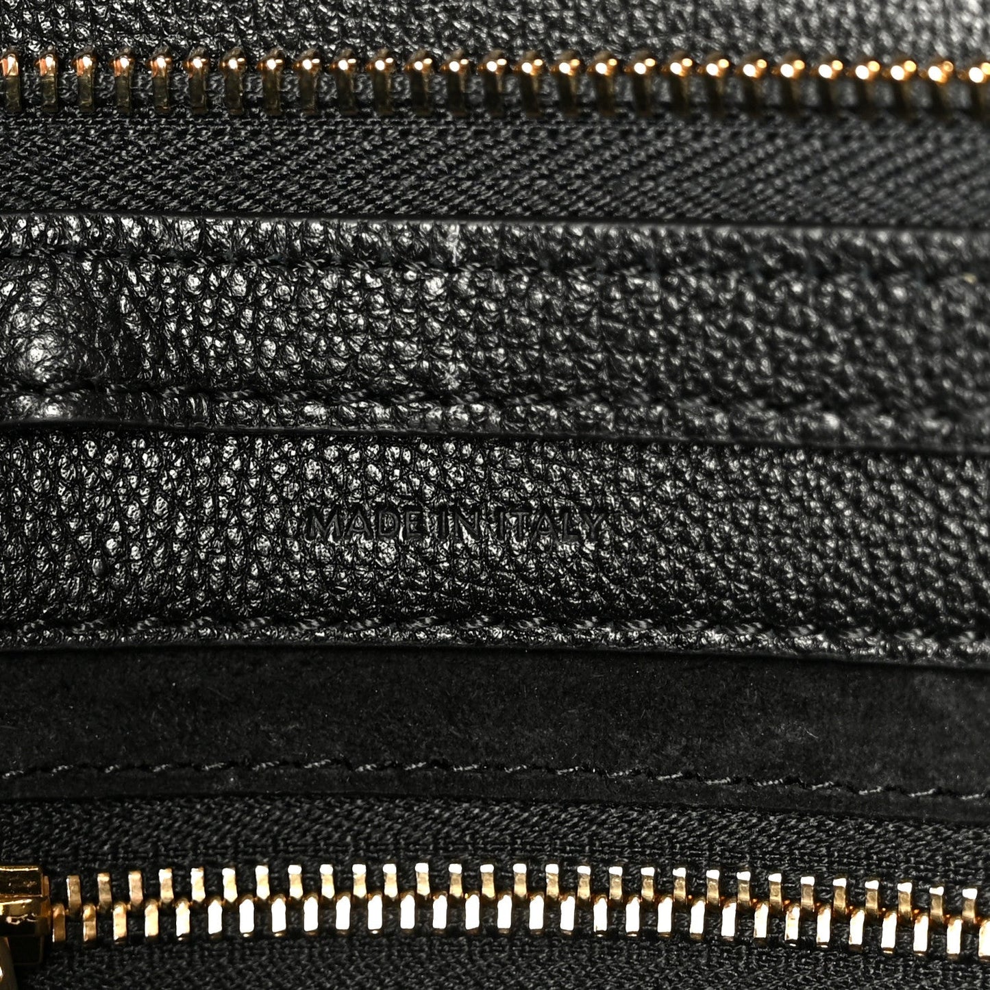 Black grained leather with “MADE IN ITALY” stamp and gold zipper trim