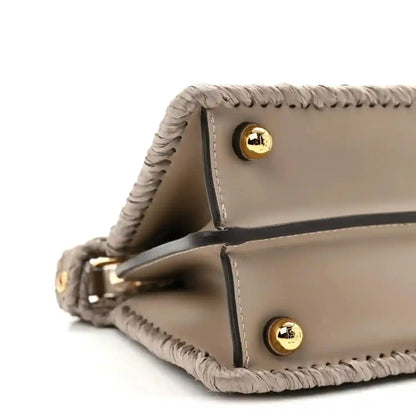 Light gray leather flap satchel with gold snap buttons and raffia edging