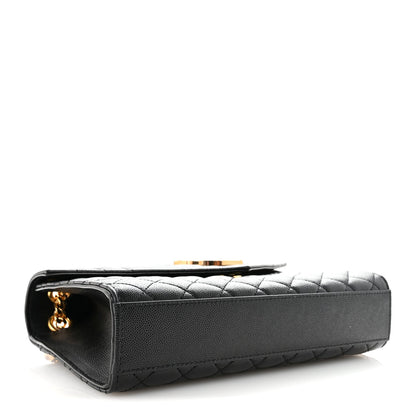 Black leather satchel end view with quilted texture and gold chain detail at the corner