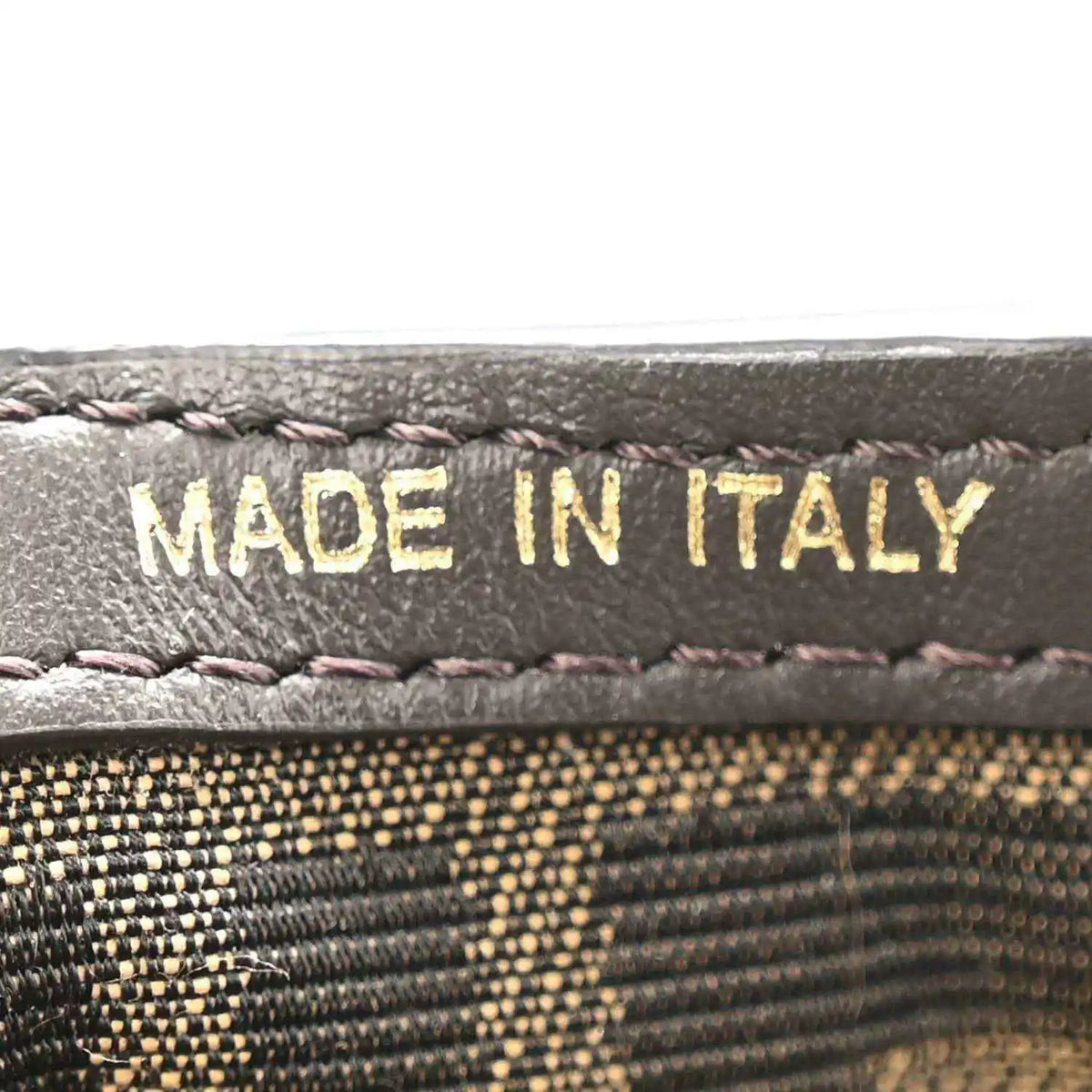 Close-up of “MADE IN ITALY” stitching on dark leather trim.