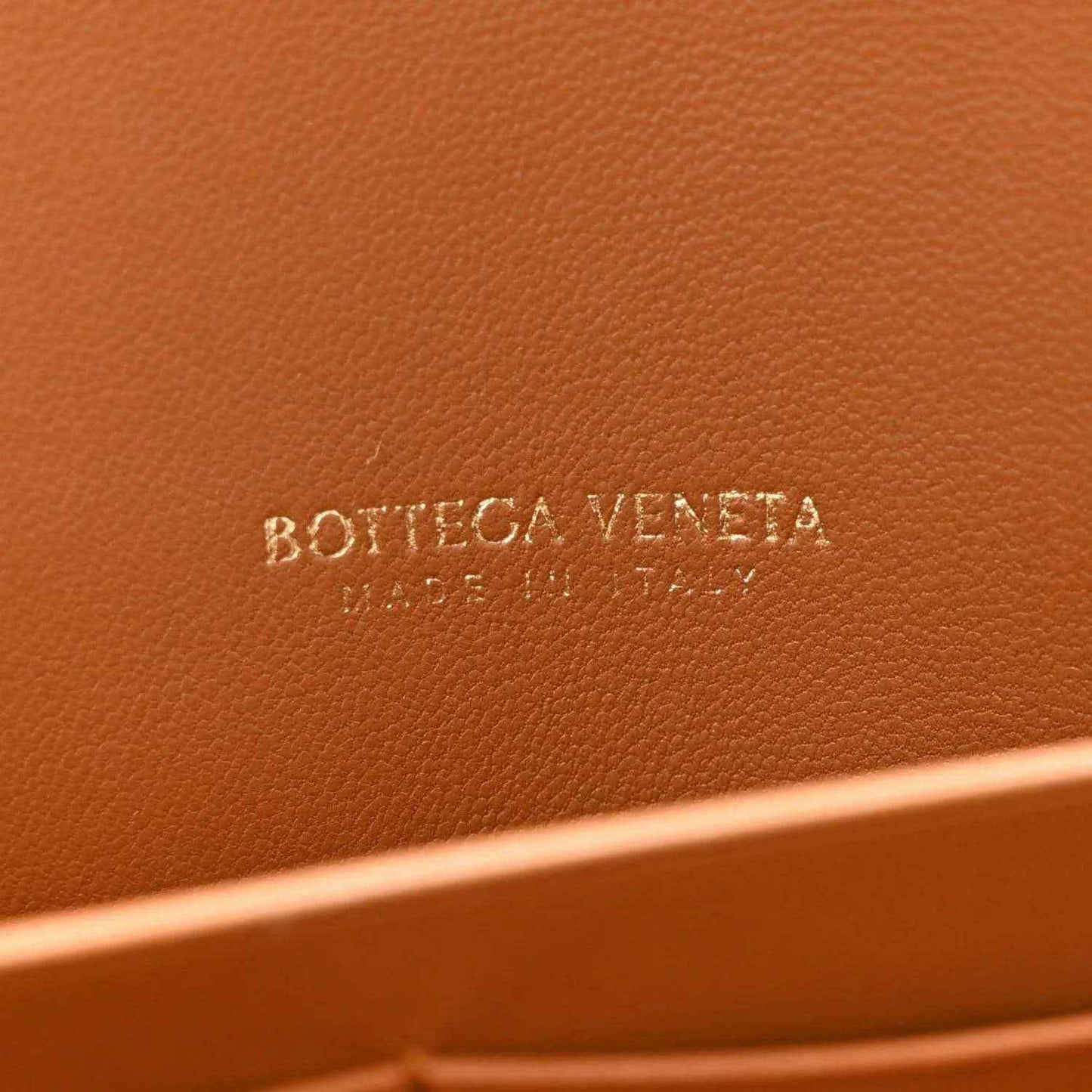 Amber suede clutch with embossed “BOTTEGA VENETA” logo on inner panel