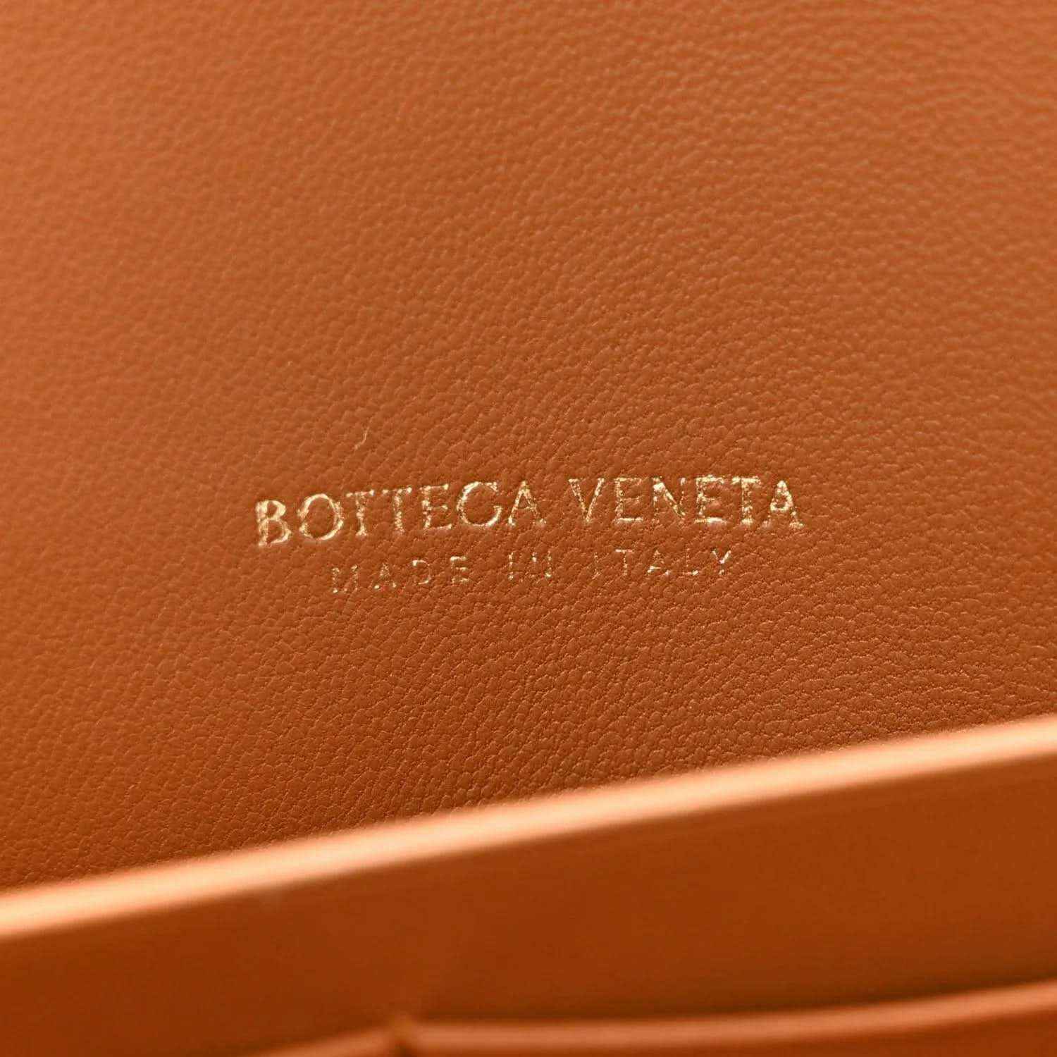 Amber suede clutch with embossed “BOTTEGA VENETA” logo on inner panel