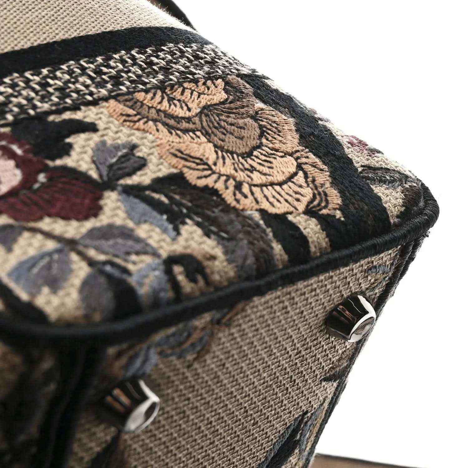 Embroidered canvas tote bag with dark floral motif and leather-trimmed corner