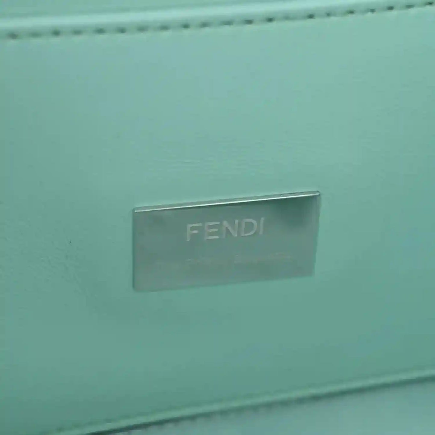 Blue baguette bag close-up of metallic FENDI logo plate