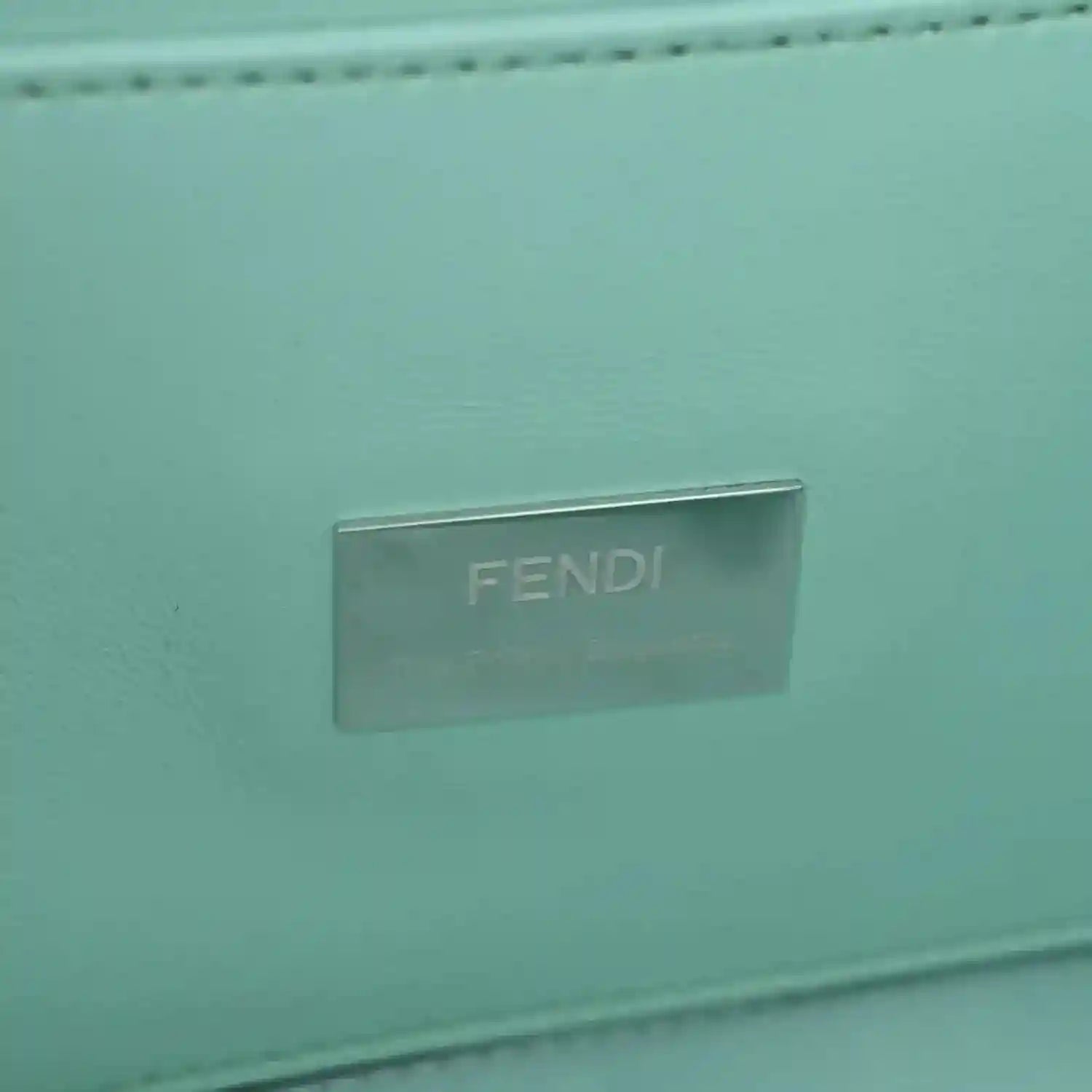 Blue baguette bag close-up of metallic FENDI logo plate