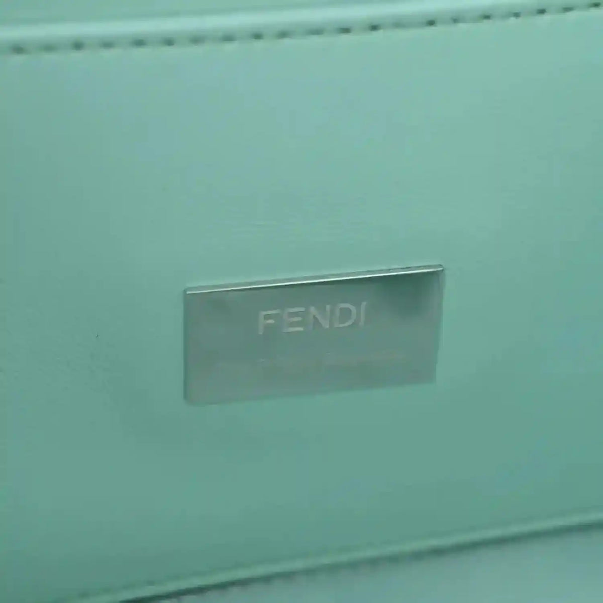 Blue baguette bag close-up of metallic FENDI logo plate