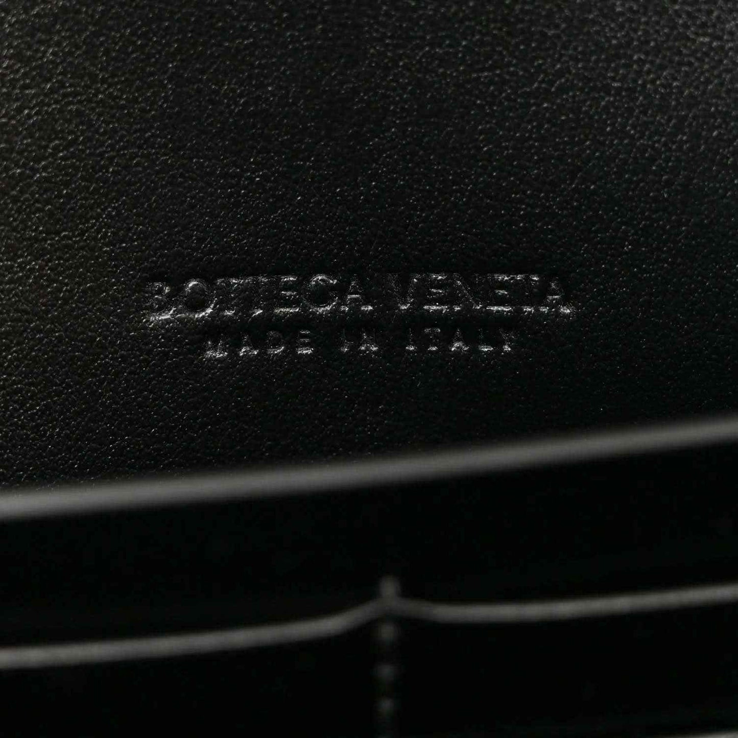 Bottega Veneta leather clutch brand imprint on black leather