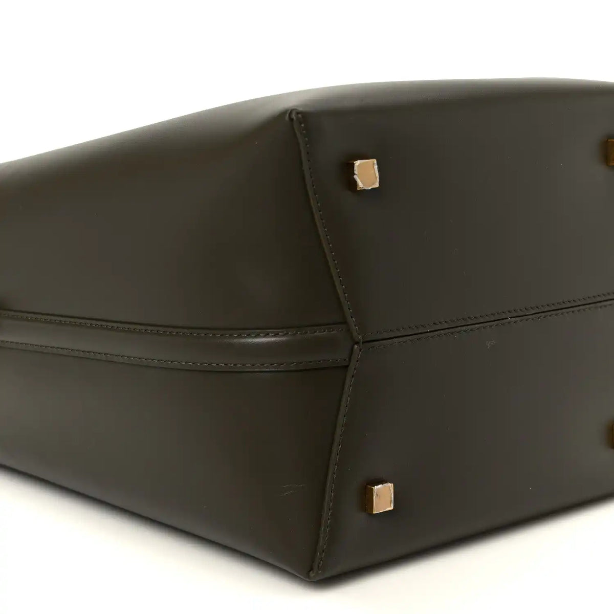 Saint Laurent bucket bag bottom corner view in deep musk leather with gold studs.