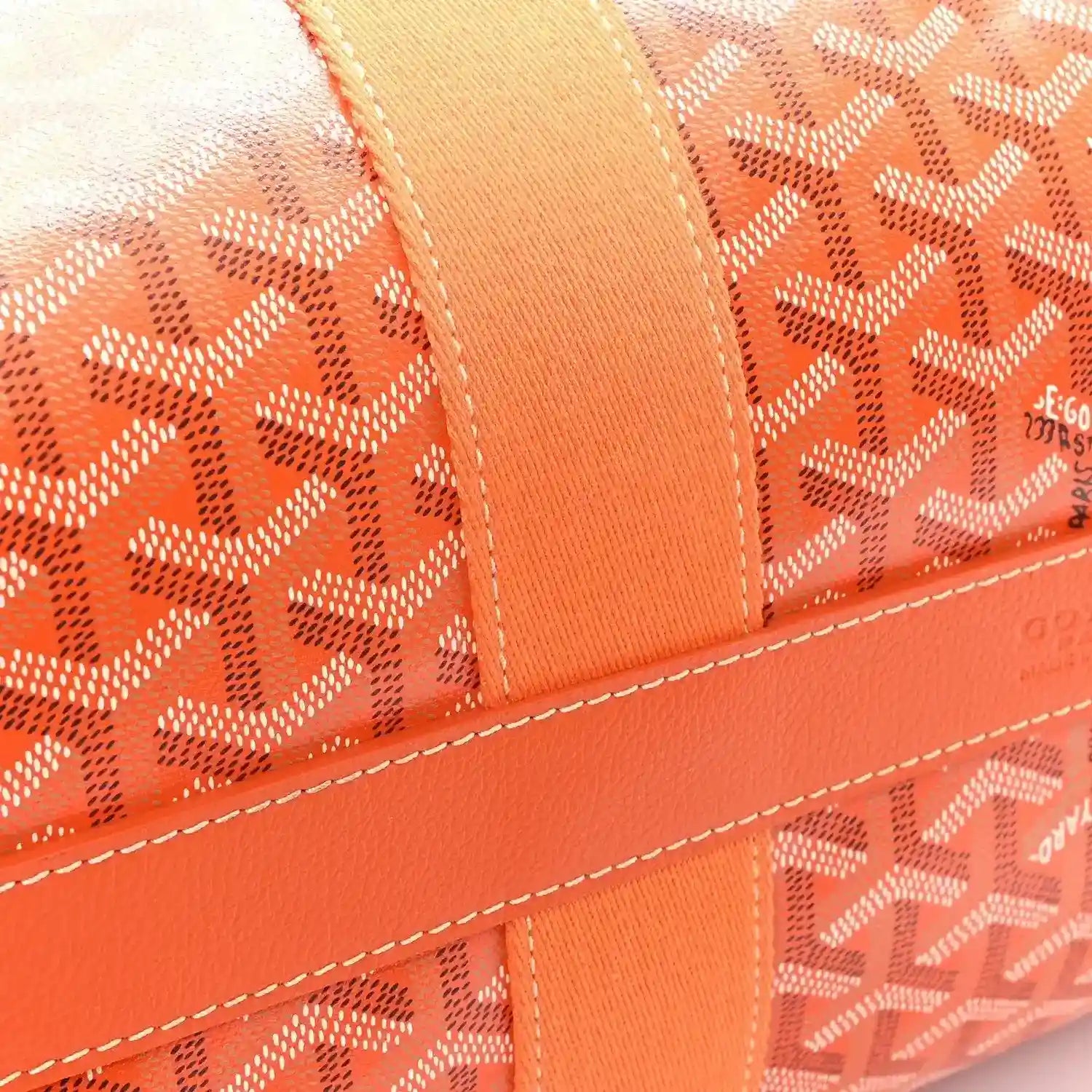 Orange canvas barrel duffel bag with monogram pattern and stitched trim detail.
