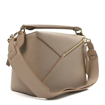 Sand leather bag front with crossbody strap, diagonal seams, and gold-tone zipper pull.