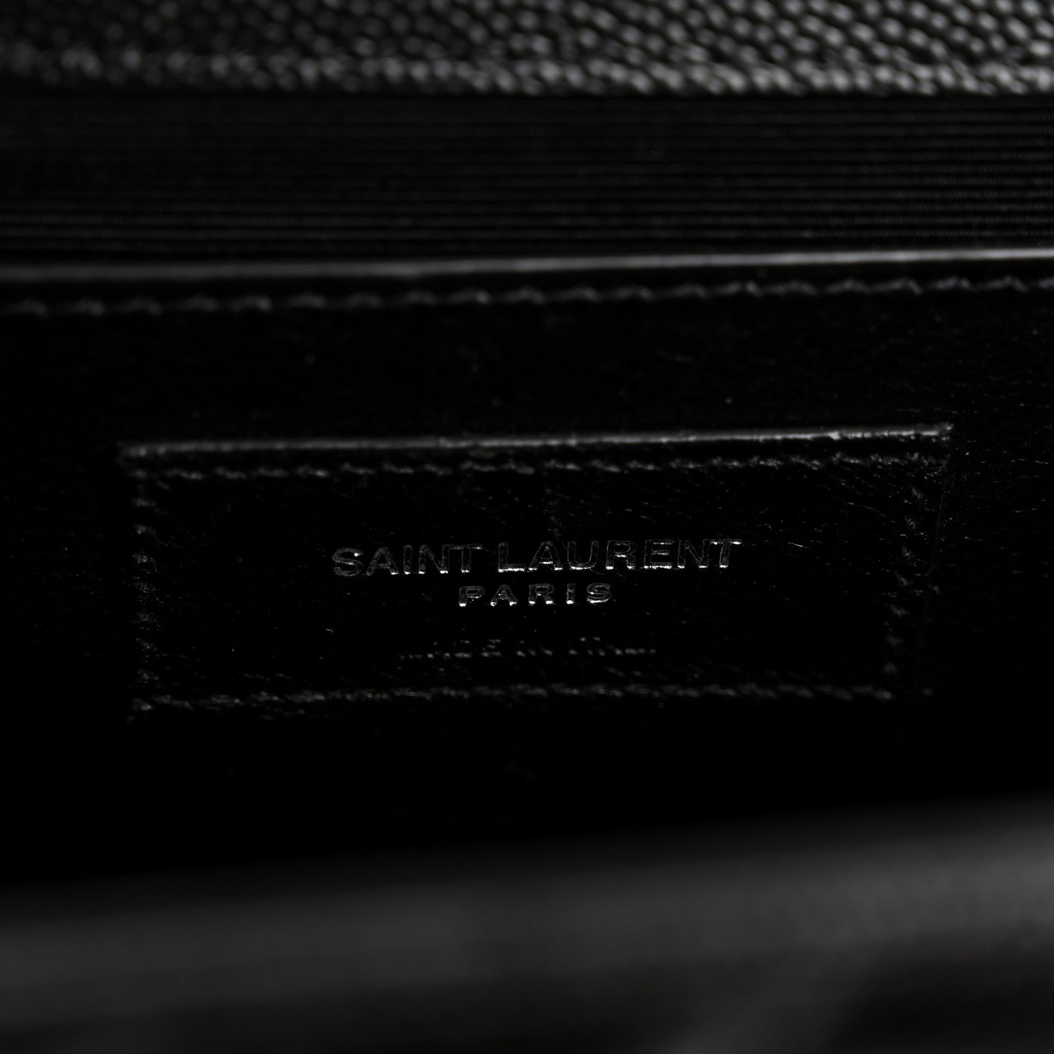Black leather satchel label with embossed SAINT LAURENT text