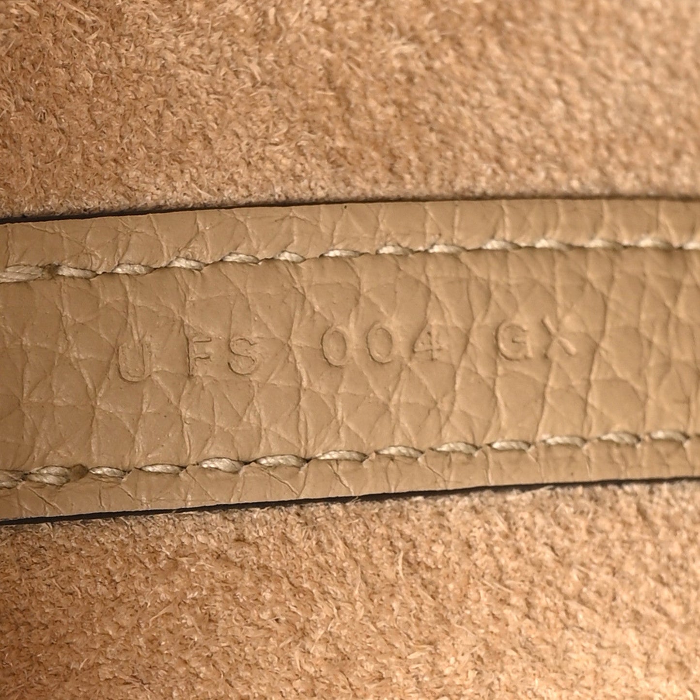 Beige leather seam with embossed maker stamp and textured grain