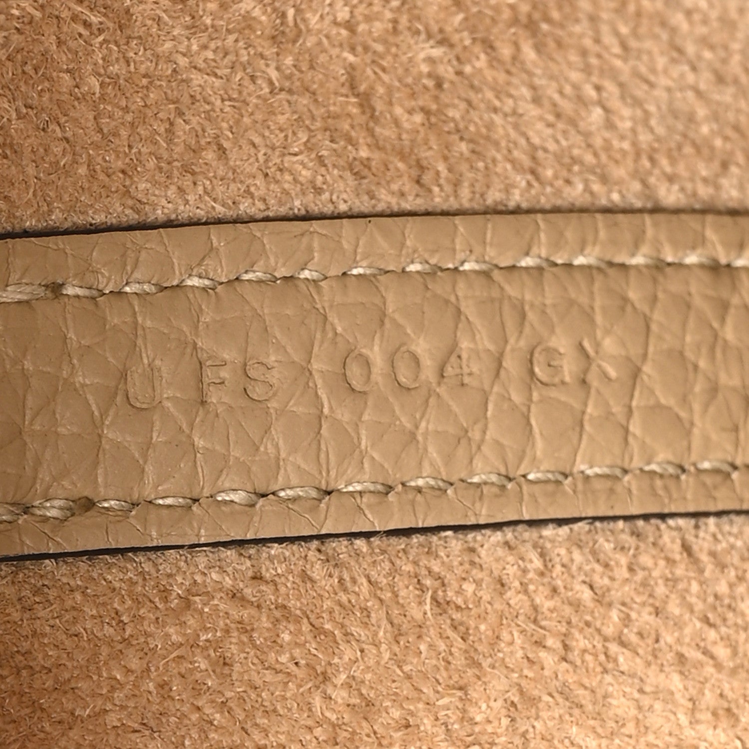 Beige leather seam with embossed maker stamp and textured grain
