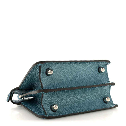 Blue leather satchel underside with corner snap buttons and braided edge trim.