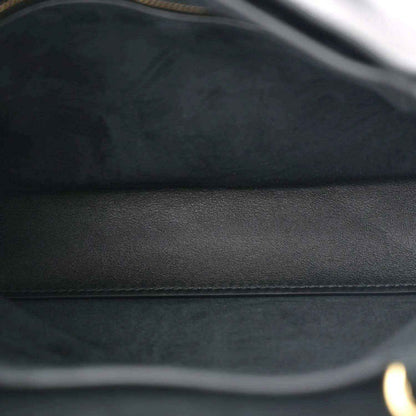 Black leather bag close-up showing smooth panel and subtle stitching seam.