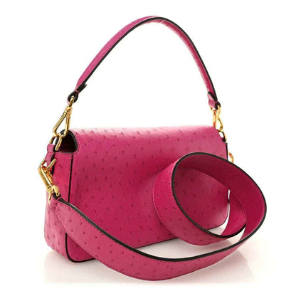 Pink ostrich leather baguette handbag with top handle, shoulder strap, and gold clasp
