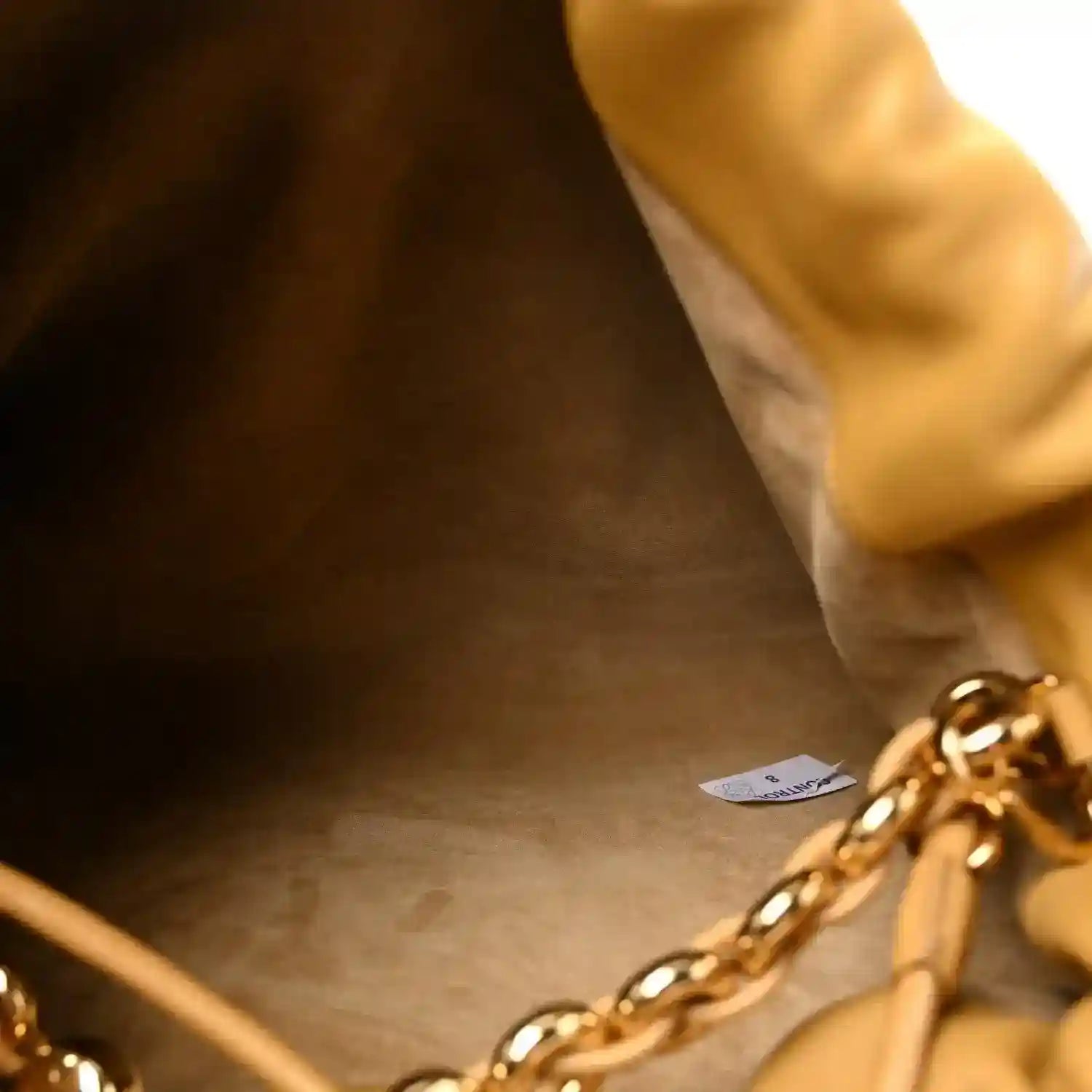 Close-up of tan leather clutch interior with gold-tone chain hardware