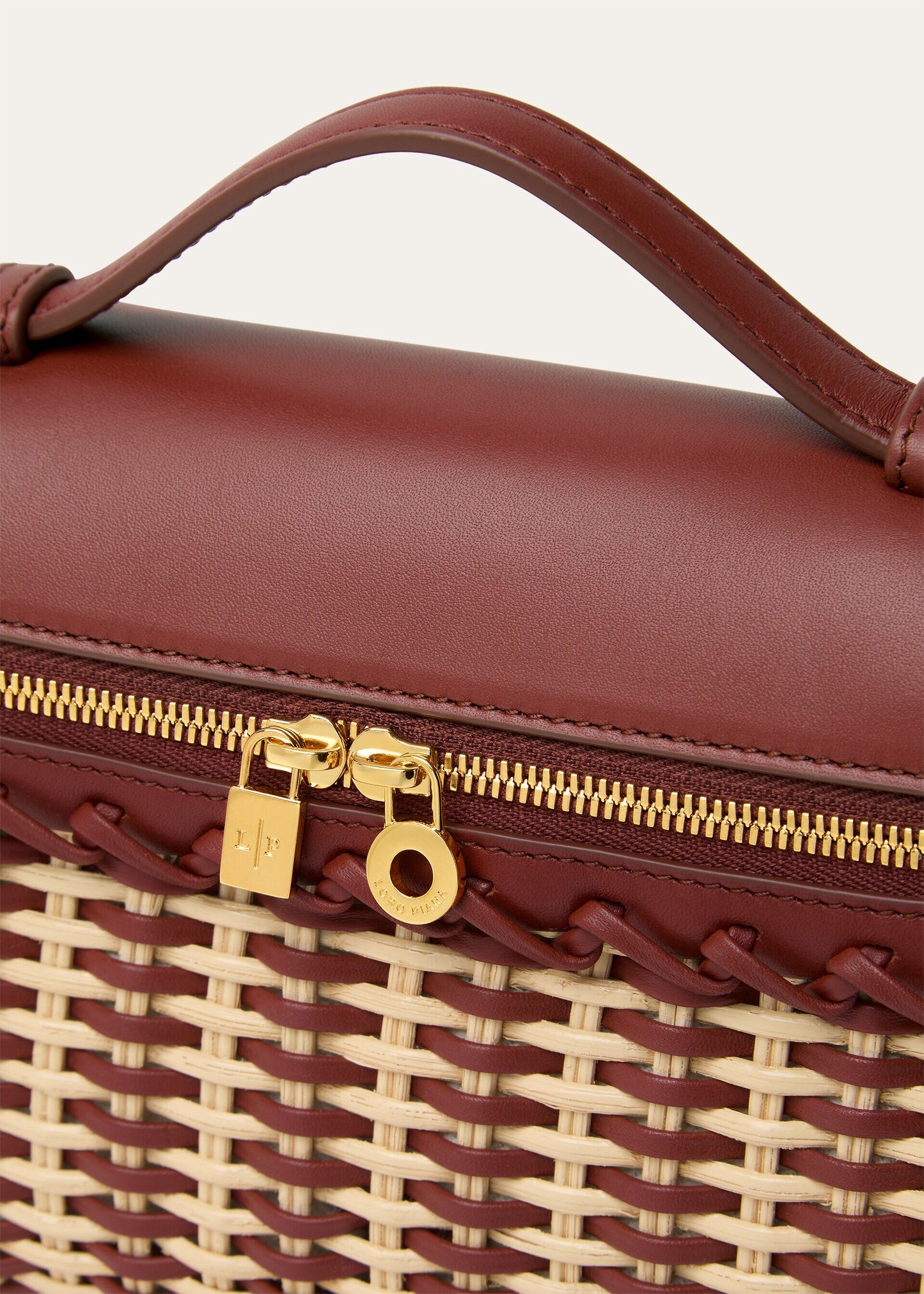 Wicker and calfskin pouch close-up of gold zipper pull and woven edge detail.