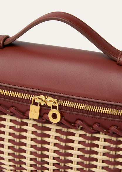 Wicker and calfskin pouch close-up of gold zipper pull and woven edge detail.