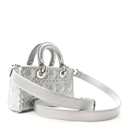 Small metallic silver handbag with geometric canage texture, top handles, and crossbody strap.