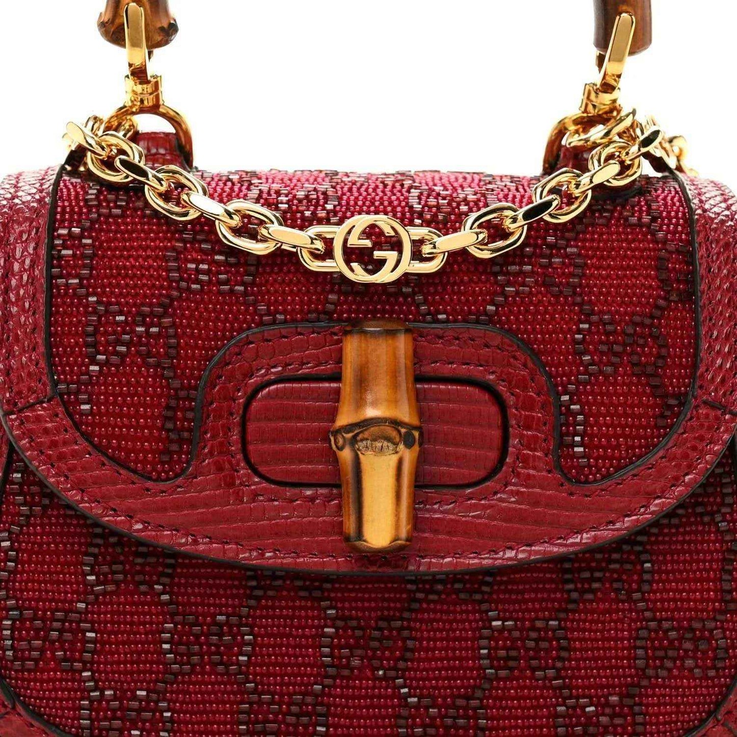 Red mini top-handle bag front close-up with gold chain link trim and bamboo-look bar clasp.