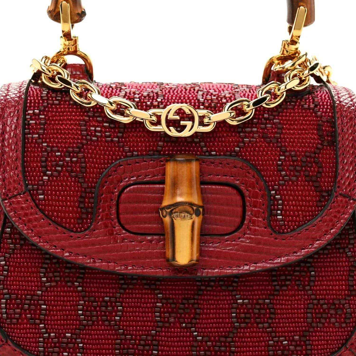 Red mini top-handle bag front close-up with gold chain link trim and bamboo-look bar clasp.
