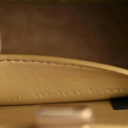 Petite satchel bag interior leather close-up with embossed text and stitched trim.