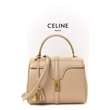 Nude small top-handle bag with top handles, shoulder strap, and gold hardware