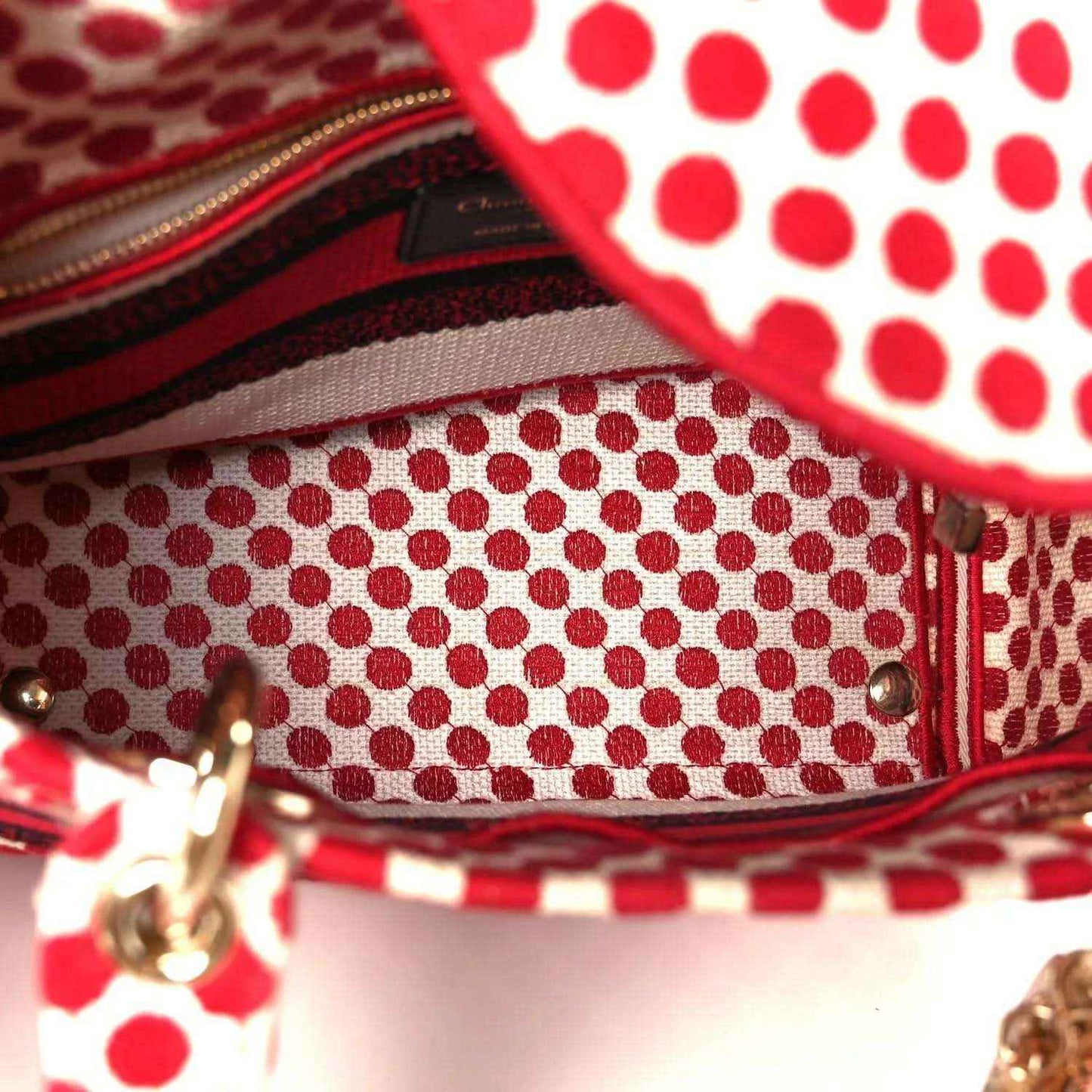 Polka dot canvas bag opening with gold zipper and red fabric trim