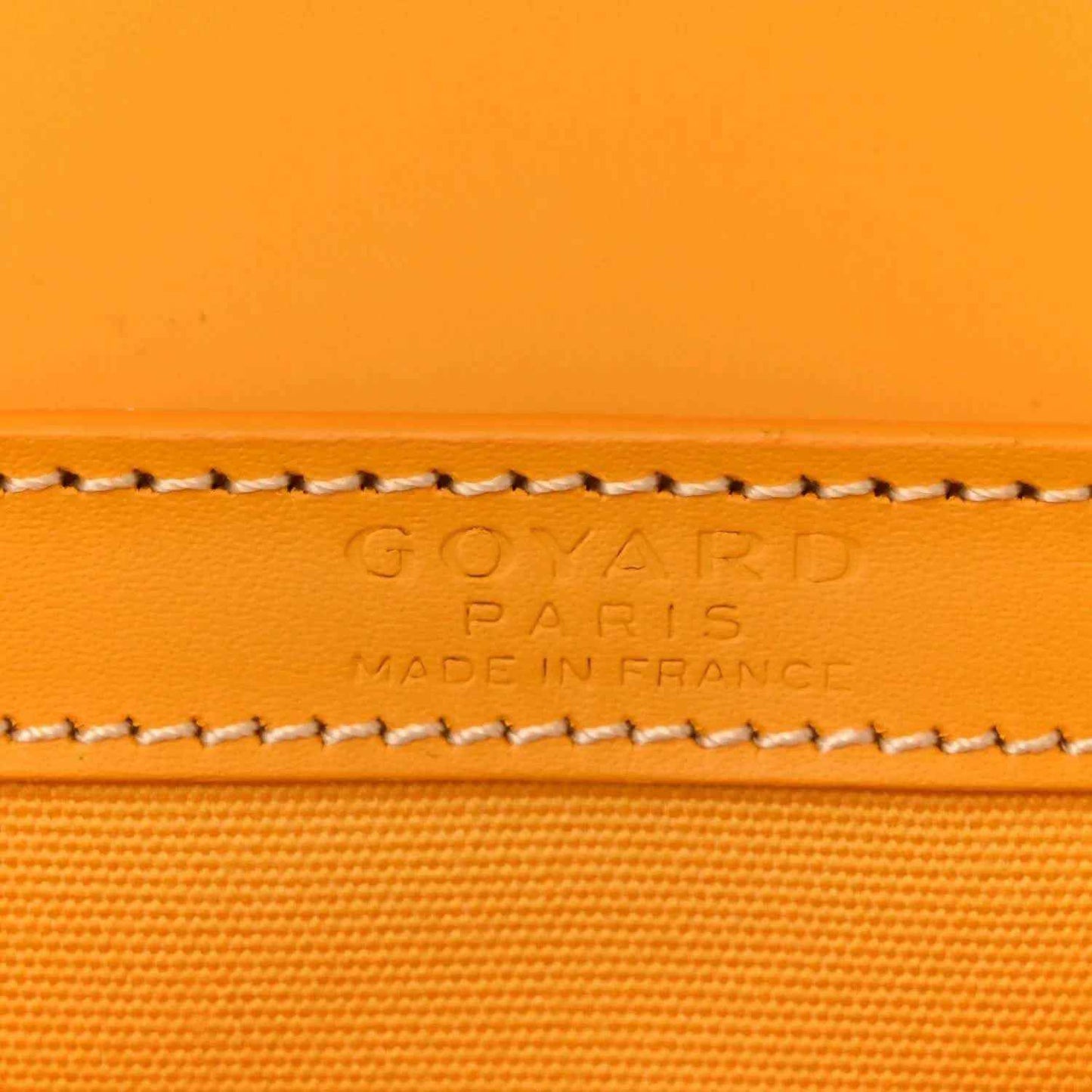 Close-up of yellow canvas edge with embossed brand text and contrast stitched trim.