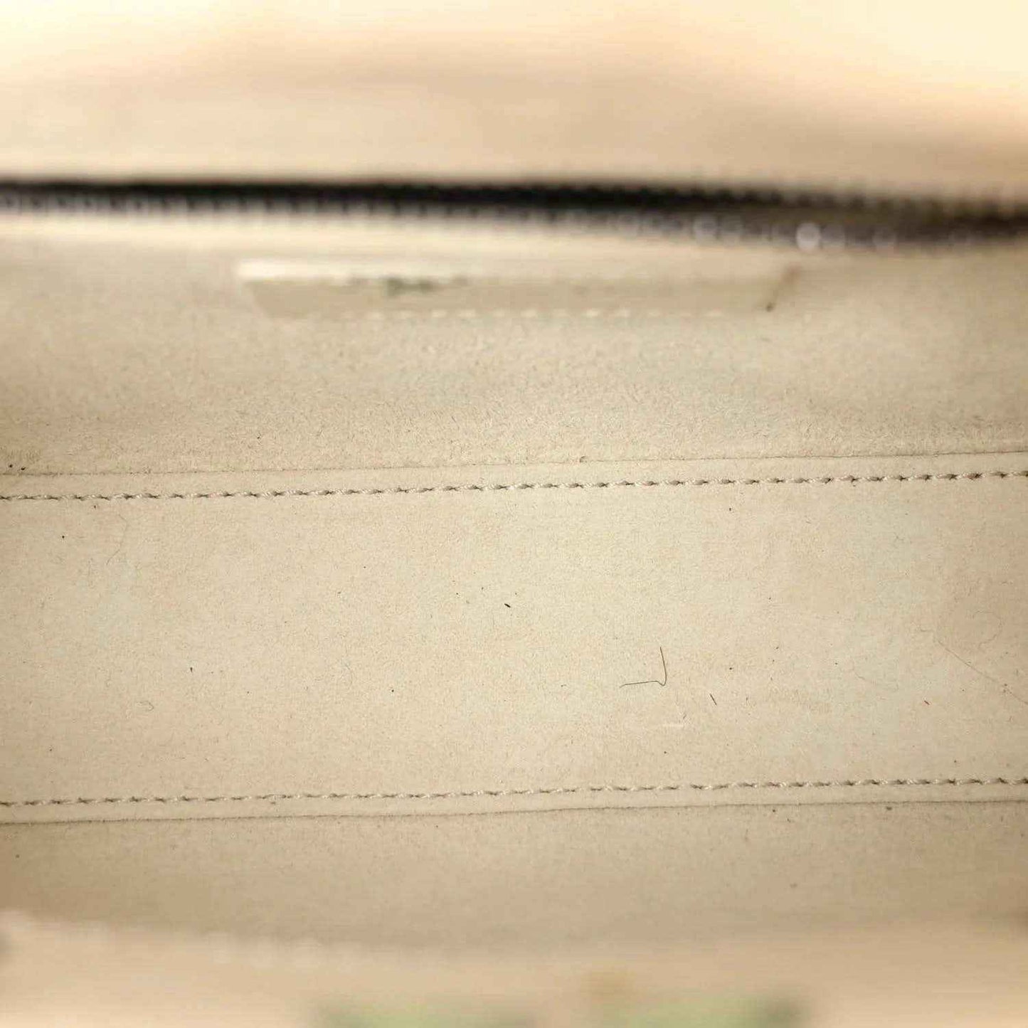 Mini Lady Dior bag close-up of stitched leather seam in white