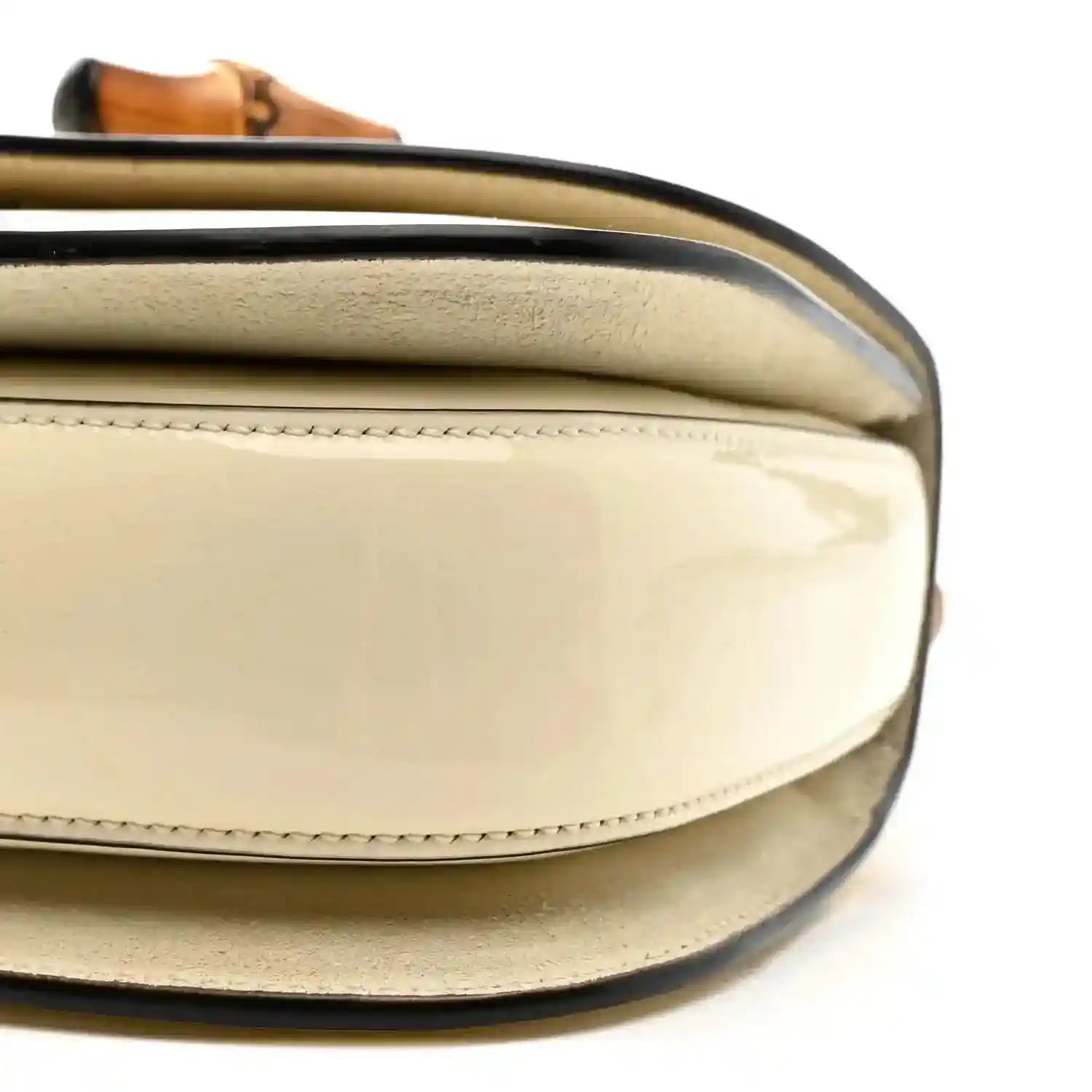 Close-up of white mini handbag flap with curved opening and bamboo handle